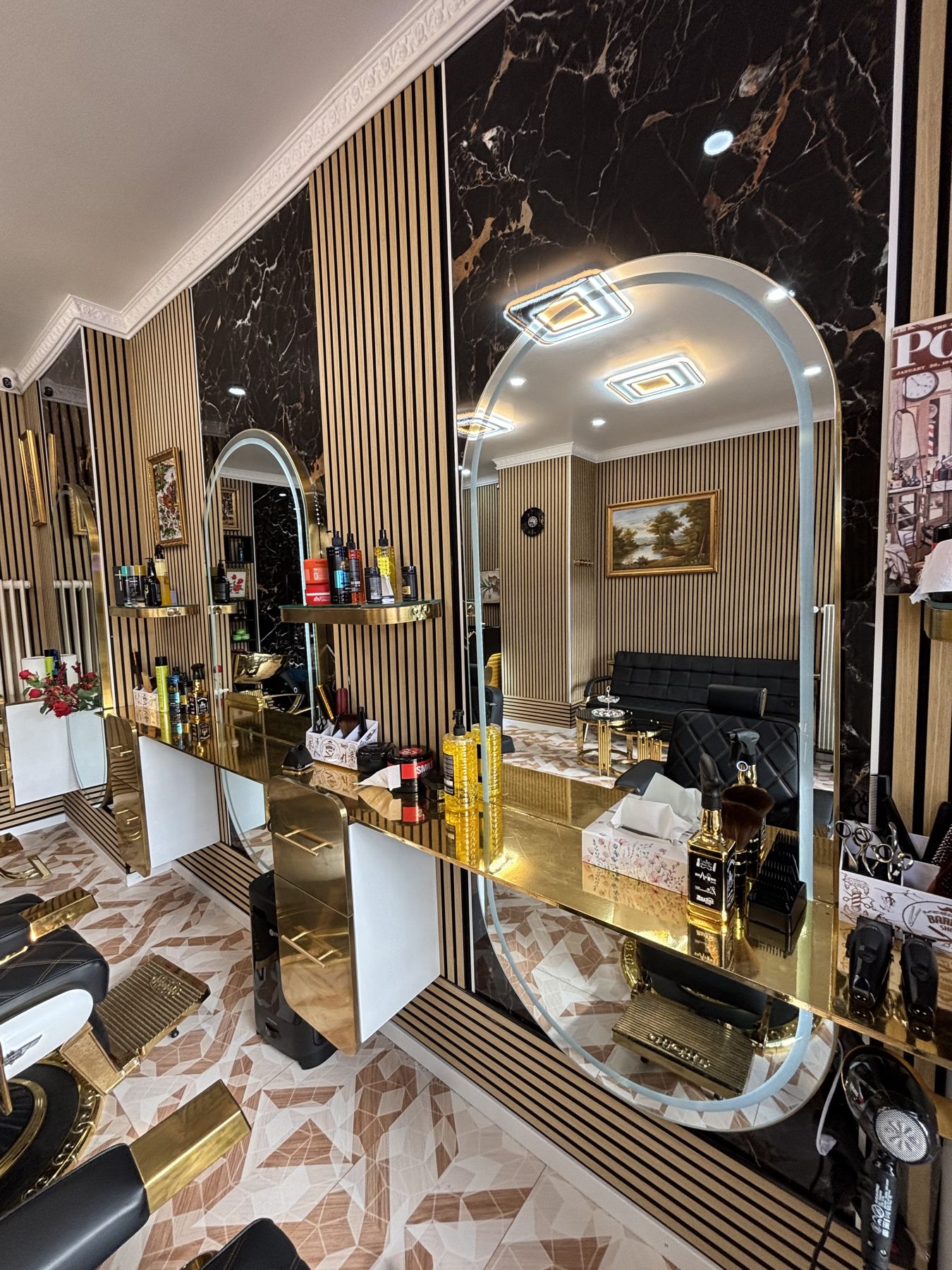 Miroir en arche et produits dorés devant le mur de marbre noir